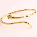 Close-up of golden snake bracelet featuring green gemstone eyes on soft pink background - Minimalist Polished With Green Eyes Style (Style 3)