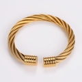 Macro view of gold twisted wire cable bracelet with cylindrical end caps and texture - Gold