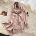 Pink soft cashmere scarf with fringe tassels shown on a beige plush background - Romantic Pink