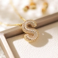 Gold-plated letter S necklace with sparkling zircons on a soft beige background - Letter S (18k Gold + Bead Chain)