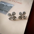 Vista detallada de pendientes de flor plateados con cristales sobre fondo de una revista - Pin de Plata-Pendientes de Botón de Flor de Cristal Gris