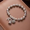 Detail of silver beaded bracelet with fortune bag and horse charms on brown leather - Wealth Horse
