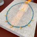 Detailed shot of ethnic beaded necklace with blue stones and golden metal discs on a notebook - Necklace - Gold - Blue