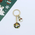 Close-up of a Christmas enamel keychain with Santa and snowflake charms on golden chain - Wreath and Snowman