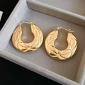 Detail view of gold hoop earrings with star geometric textured engraving in a jewelry box - Gold