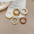 Flat lay of five tortoiseshell and cream acrylic resin rings on a warm beige background - White-Coffee Set (Five Pieces)