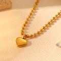 Macro shot of gold stainless steel heart pendant necklace on a natural textured surface - Gold Bead Necklace (I216)