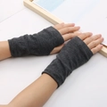 Close-up of dark grey knitted fingerless gloves worn on hands over a white background - One Size / Dark Gray