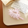 Pink spotted white shell hair claw clip shown on a beige minimalist display tray - Seashell Light Pink (Plastic)