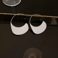 Makroaufnahme silberner halbmondförmiger Creolen aus poliertem Edelstahl - Sonnenhut-Ohrhaken-Stil / Silber
