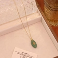 Dettaglio di una collana vintage dorata con pendente verde e pietra rossa stile francese - Aventurina Verde