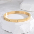 Elegant gold starburst bangle with inlaid clear zircons and polished mirror finish - Bangle