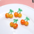 Dettaglio di quattro ciondoli a ciliegia in resina arancione su un piatto bianco - 4# Ciliegia Gialla Grande 1pz