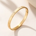 Bracciale rigido dorato in acciaio con incisione JESUS e griglia, vista a 45 gradi - Oro