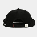 Detail of adjustable silver metal buckle and red logo tag on the black docker hat - Adjustable / Black