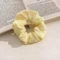 Pale yellow oversized scrunchie with bubble waffle texture on a vintage book page - Puff Milk Yellow