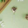 Golden heart-shaped cake candle with metallic finish and white stand on green background - Heart / Champagne