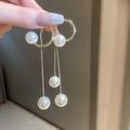 Dettaglio di orecchini geometrici dorati con lunghe nappe di perle e finiture eleganti - Stile nappa perla dorata