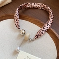 Détail du collier foulard en soie léopard rose avec breloques perles sur plateau en bois - Léopard Rose - Style Boule