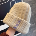 Gorro de punto grueso beige con orejeras y bordado de X morada para invierno - Blanco Roto