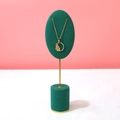 Golden necklace with floral zircon pendant displayed on a dark green velvet stand - Green