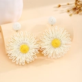 Detailed view of handmade woven raffia daisy earrings with white petals and yellow centers - White