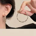 Detailed view of silver oversized twist-textured hoop earrings with metallic shine - Polished Irregular Twisted Hoop / Silver