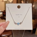 Silver bow necklace with blue bead and starfish charms on a white display card - Starfish Shell Pendant / Silver/Blue Bead