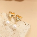 Macro view of gold heart frame and round pearl pendant on a beige stone surface - Heart Pearl