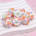 Handmade white acrylic beads with colorful polka dots and strawberry patterns on a tray - Orange Strawberry + Purple Heart + Purple Ring