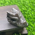 Dark grey natural stone dragon head figurine on a wooden stand with a green background - Flame Stone
