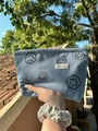 Dettaglio della borsa da trucco in velluto a coste azzurro con motivi di sorrisi - Blu