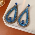 Dettaglio macro di orecchini a goccia in zircone blu con intricato design vintage traforato - Blu