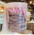 Close-up of wave textured hair ties in a clear jar held by hand for scale display - Pink