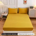 Solid ginger yellow fitted sheet set with matching pillowcases on a minimalist bed - Turmeric