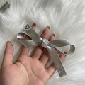 Close-up of silver bow hair clip featuring shiny pink and blue rhinestones on plush background - Silver Thick Edge Bow Hair Clip