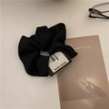 Chouchou rétro noir avec étiquette tissée sur un fond minimaliste avec lunettes - Chouchou Satiné Noir avec Étiquette