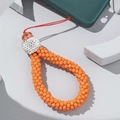 Macro shot of orange crystal beads and rhinestone accents on a braided mobile phone strap - Orange