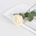 Single cream velvet artificial rose with green stem and leaves on a magazine background - Small Velvet Champagne