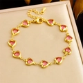 Detail of gold chain bracelet featuring ten faceted pink heart crystals on leather texture - Pink Heart (B1666)