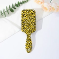 Close-up of yellow leopard print hairbrush with air cushion on a floral background - Yellow Leopard
