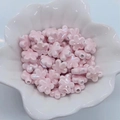 Macro di perline di ceramica rosa perlata a forma di fiore dentro una piccola ciotola bianca - Rosa Chiaro