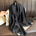 Detail of soft black satin long scarf styled elegantly on a brown leather sofa - Black