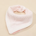 Detail of pink cotton muslin baby bib showing soft waffle texture and secure snap buttons - White + Pink