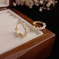 Golden twisted hoop earrings with small white pearls displayed in a wooden jewelry box - Edelweiss Pearl Studs / Gold