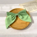 Close-up of a large green fabric bow hair clip placed on a rustic wooden tray - Two-Layer Bow Spring Clip / Avocado Green