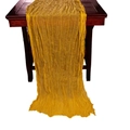 Yellow cheesecloth table runner with crinkle texture on dark wood table surface - Yellow