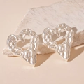 Detail of silver heart earrings with liquid metal texture on a textured stone surface - Silver Matte