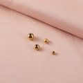 Primer plano de cuentas espaciadoras de acero dorado sobre tela rosa con textura - 5mm (Agujero de 1.2mm) / Chapado en Oro de 18K
