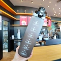 Close-up of matte gradient black sports water bottle with motivational time markers - 1000ml / Black Lid Gradient